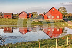 Several red wooden houses reflected in pond