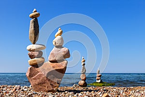Several Rock zen pyramids of stones of different shapes on a background of blue sky and sea