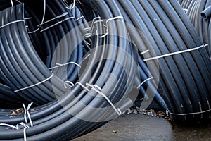 Several rolled up small diameter polyethylene pipes for laying high voltage electric cables underground. Warehouse or