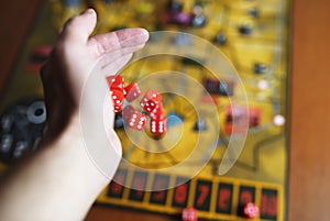 Several rolling red dice fall on a table with boardgame. Gameplay moments