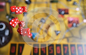 Several rolling red dice fall on a table with boardgame. Gameplay moments