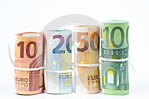 Several rolls of euro banknotes stacked by value from ten, twenty, fifty and one hundred euros isolated on white background.