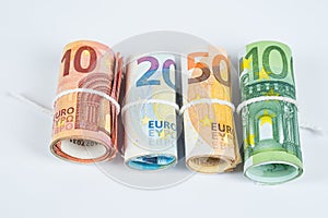 Several rolls of euro banknotes stacked by value from ten, twenty, fifty and one hundred euros isolated on white background.