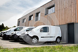 Several row of white service cars vans and trucks parked in parking lot for sale