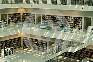 several rows of books on white tables at a library with multiple levels and shelves of