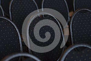 Several rows of empty and upholstered chairs in the auditorium, dark tone.