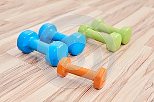 Several rubberized dumbbells of different weights and colors lie on the floor