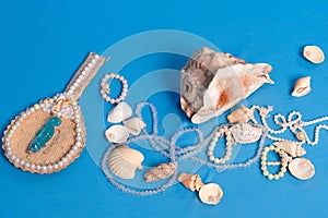Several sea shells, necklaces and mirror scattered on the blue studio floor