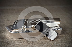 Several silver bars of various weights on a textile texture