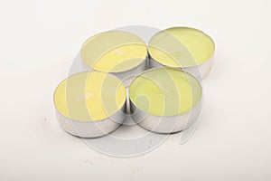 Several small colored candles in aluminum casings on a white background. Close up