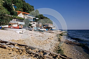 Several small fishing boats lie on the pebble beach of a colorful fishing village of Kavarna, Bulgaria, with a view of the