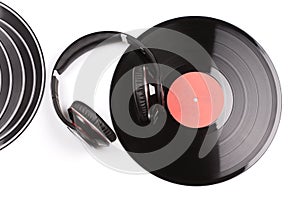 Several small and one big black vinyl records beside elegant headphones.