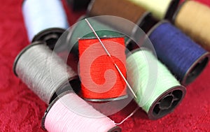 Several spools of thread with a sewing needle