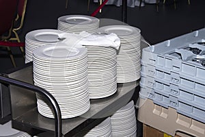 Several stacks of plates are on the waiter`s mobile table, a preparatory stage for serving tables.