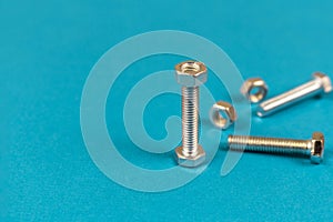 Several steel bolts and nuts on a blue background. Close-up