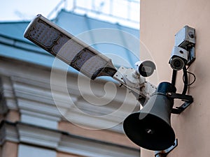 Several surveillance cameras on the wall of a house in Moscow, Russia. LED flashlight spotlight and loudspeaker on a city street.