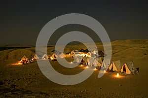 A several tents camp on the beach at night