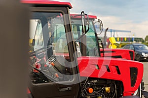 Several tractors are parked in a neat row next to each other in a field or farmyard