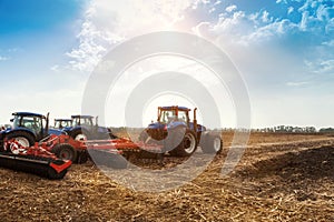 Several tractors plows the field, cultivates the soil for sowing grain. The concept of agriculture