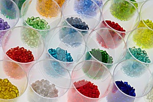 several transparent colored plastic resin granulates in test glasses