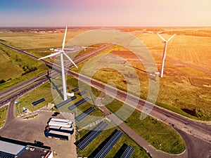 Several trucks parked near solar panels and two wind power stations