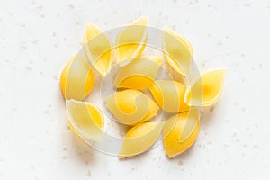 Several uncooked conchiglie pasta pieces on gray