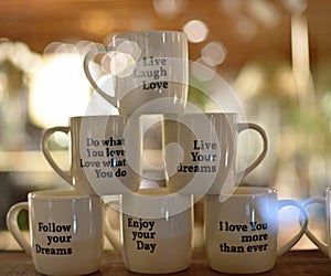 Several White Cups stacked on top that read follow your dreams, live, love, laugh and do what you love