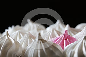 A several white meringues with one pink among other