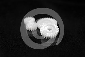 Several white plastic gears on a black mirror background. Mechanical repair. Fix. Reflection. Repair shop. Cogwheels. Elements of