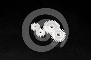 Several white plastic gears on a black mirror background. Mechanical repair. Fix. Reflection. Repair shop. Cogwheels. Elements of