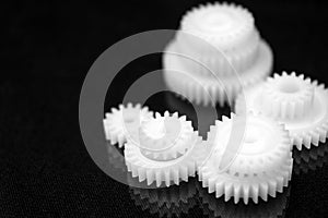 Several white plastic gears on a black mirror background. Mechanical repair. Fix. Reflection. Repair shop. Cogwheels. Elements of