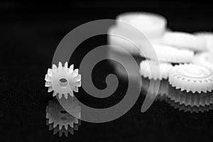 Several white plastic gears on a black mirror background. Mechanical repair. Fix. Reflection. Repair shop. Cogwheels. Elements of