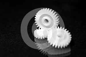 Several white plastic gears on a black mirror background. Mechanical repair. Fix. Reflection. Repair shop. Cogwheels. Elements of