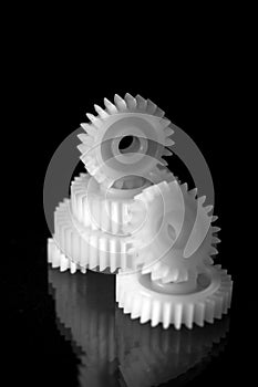 Several white plastic gears on a black mirror background. Mechanical repair. Fix. Reflection. Repair shop. Cogwheels. Elements of