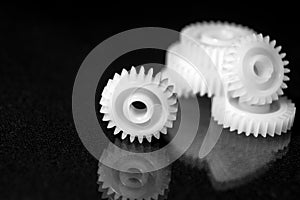 Several white plastic gears on a black mirror background. Mechanical repair. Fix. Reflection. Repair shop. Cogwheels. Elements of