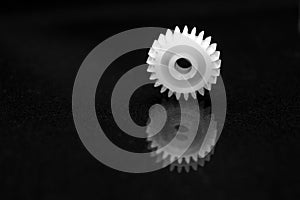 Several white plastic gears on a black mirror background. Mechanical repair. Fix. Reflection. Repair shop. Cogwheels. Elements of