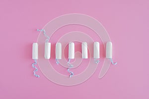 Several white sanitary tampons on a pink background.