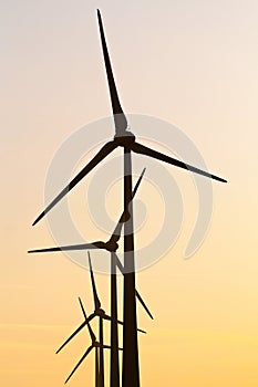 Several wind turbines in front of a beautiful sunset