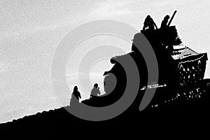 several youths playing on abandoned tank in silhouette