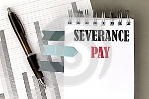 SEVERANCE PAY text on notebook with pen, calculator and chart on a grey background