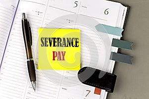 SEVERANCE PAY word on the yellow sticky with office tools on daily planner