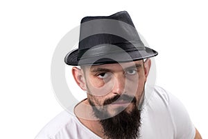 Severe bearded man in hat looking at camera isolated on white ba