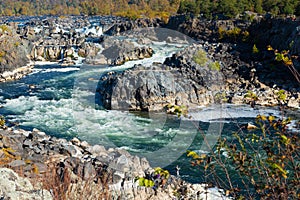Severe rapid mountain river flows among high rocks. Autumn landscape of a wide mountain river on a sunny day