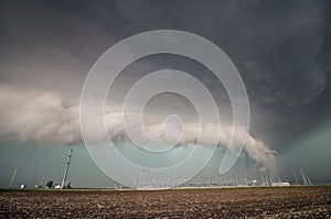 A severe thunderstorm and low shelf cloud loom over electrical equipment.