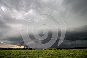 A severe thunderstorm with a shelf cloud over a green field.