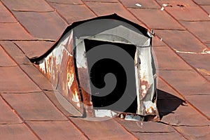 Severely damaged cracked and partially broken old roof window frame without glass on top of abandoned family house