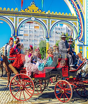 Spanish families in traditional and colorful dress travelling in a horse drawn carriages at the April Fair, Seville Fair