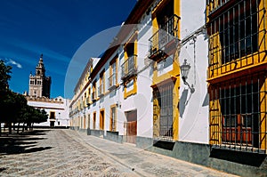 Seville Cathedral`s Moorish Giralda tower with traditdional buildings on a courtyard in Real Alcazar, Sevilla, Andalusia