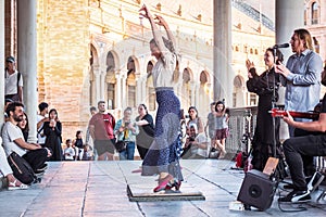 Seville, Spain - April 11, 2023: Flamenco dancer woman accompanied by street buskers guitarists Plaza de EspaÃÂ±a galleries