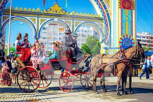 Spanish families in traditional and colorful dress travelling in a horse drawn carriages at the April Fair, Seville Fair